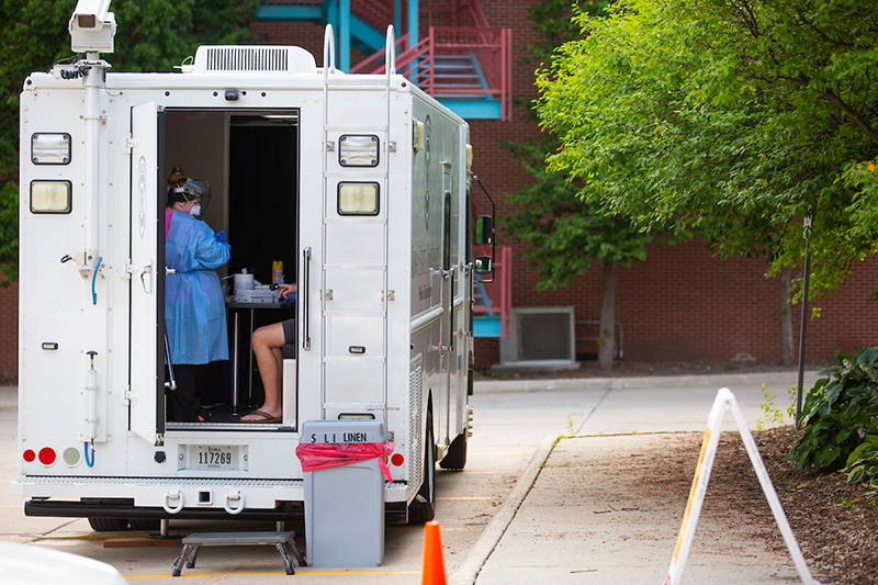 Health professional in PPE conducts COVID-19 test in mobile unit