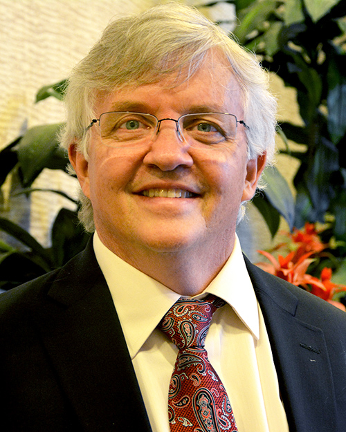 White man with glasses in tie and navy jacket