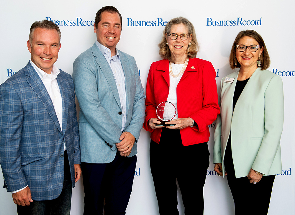 Two men and a woman flank female award recipient holding her awa