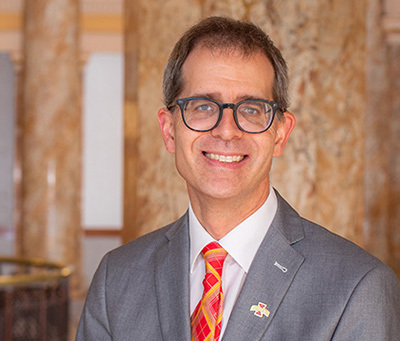 Head shot of white man in gray suit with plaid tie