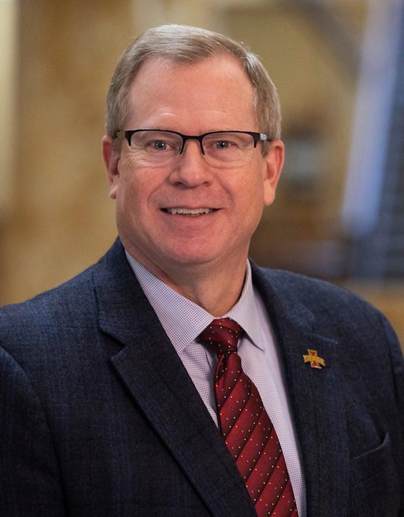 White man with glasses in red tie and navy jacket