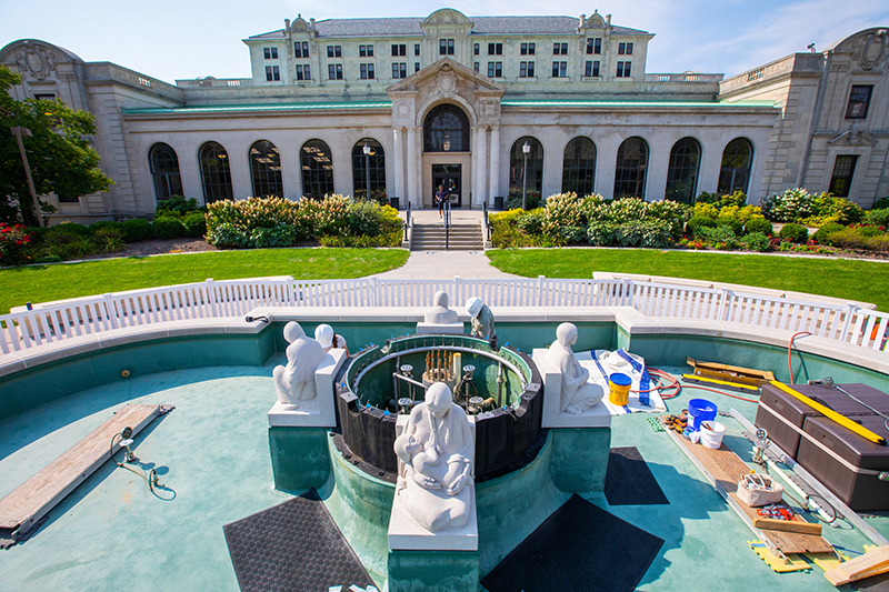 Four limestone sculptures surround fountain works in empty pool