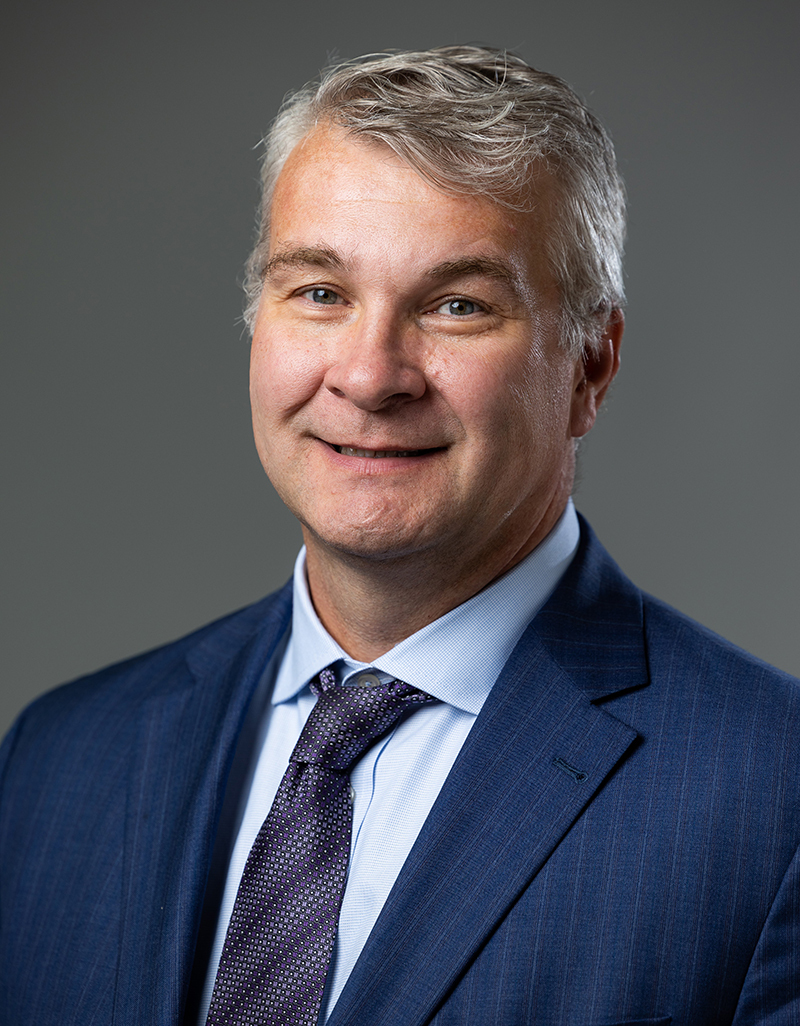 head shot of man in blue suit and tie