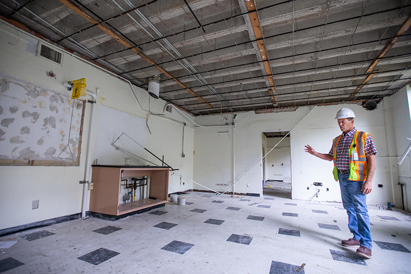 Man in construction hat stands in vacated lab room with stripped