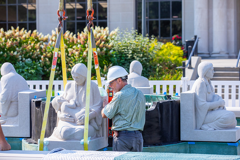 Man applies vertical level to right side of limestone maiden scu