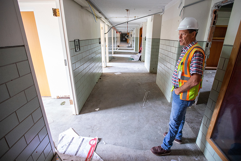 Man in construction hat stands in vacated building hallway