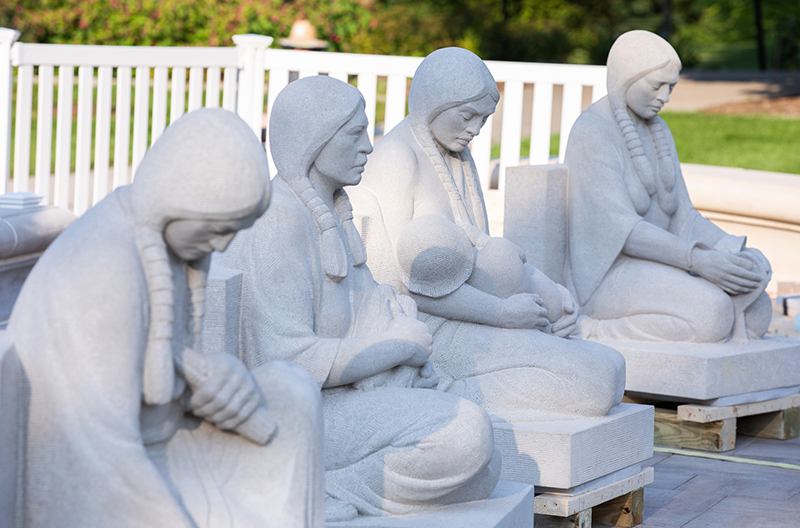 Four limestone sculptures of Native maidens in a row