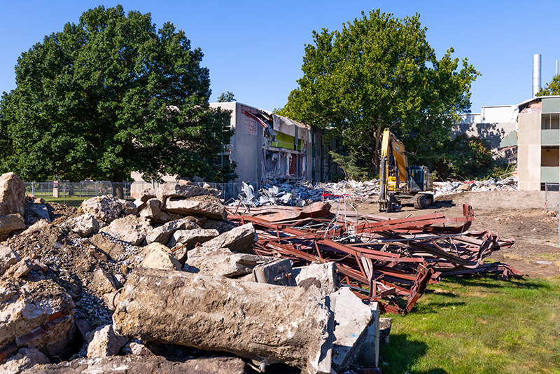 Separated piles of concrete and metal sit near building demoliti