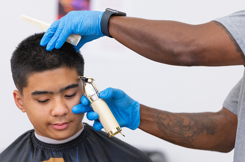 Black-haired male gets his sideburns trimmed