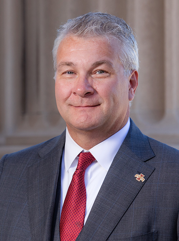 head shot of man in blue suit and red tie