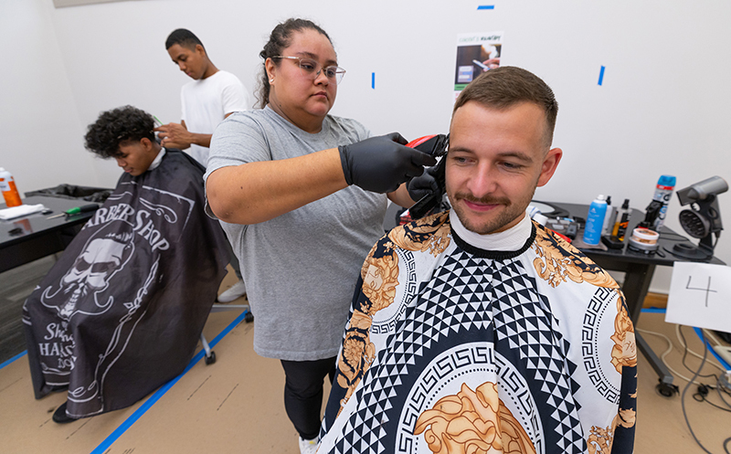 White males student with beard gets his haircut by female stylis