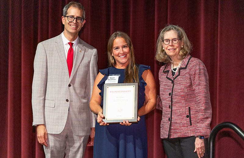 Woman with framed award, flanked by male and female leaders