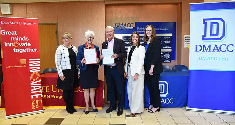 Four women and one man stand with paper copies of articulation a