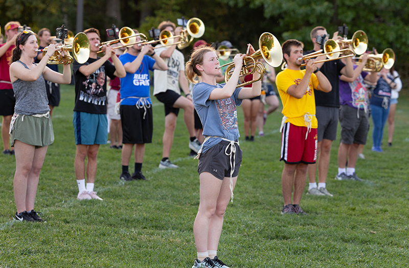 male and female students in shorts and T-shirts playing brass ho