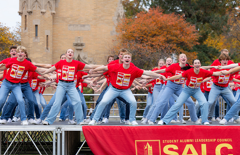 Male and female students in matching red shirts and jeans perfor