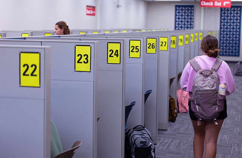 Students barely visible in testing center with privacy cubicles