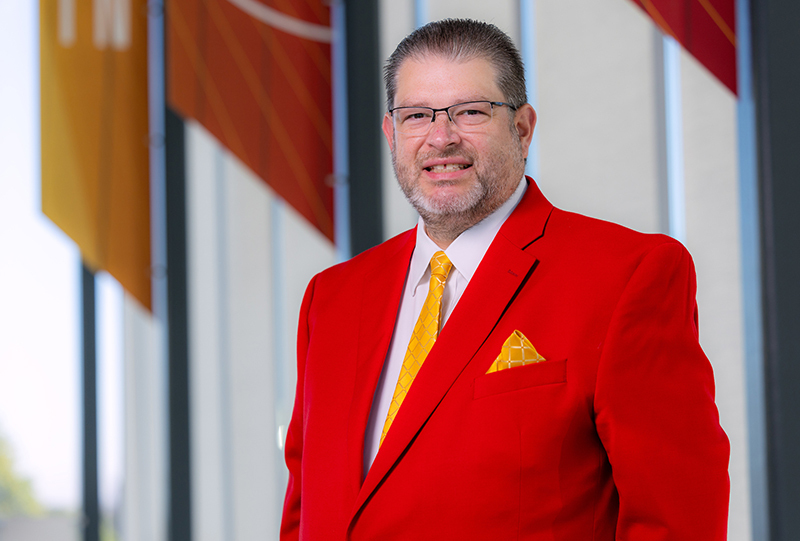 Man with beard in red suit coat and yellow tie