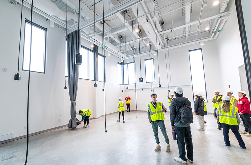 Students in hard hats and neon vests look around room with 23-fo