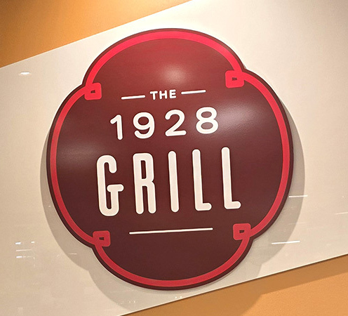 Brown, red and white circular wall sign for The 1928 Grill