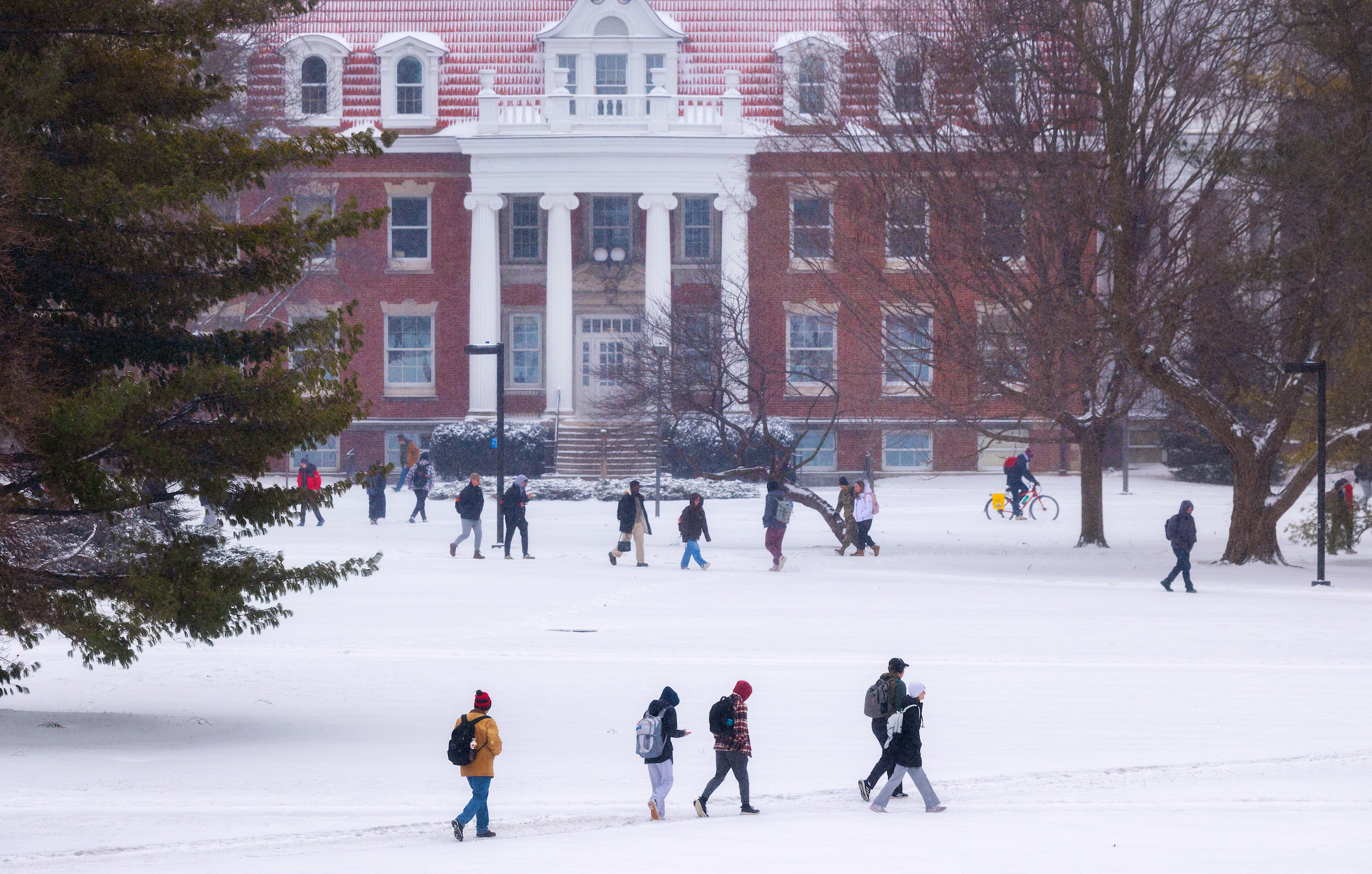 Wide angle of students walking in the snow across a lawn