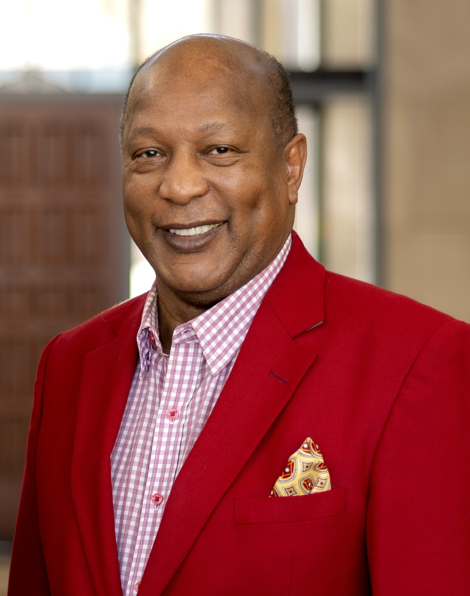 head shot of black man in red blazer and red-checked shirt