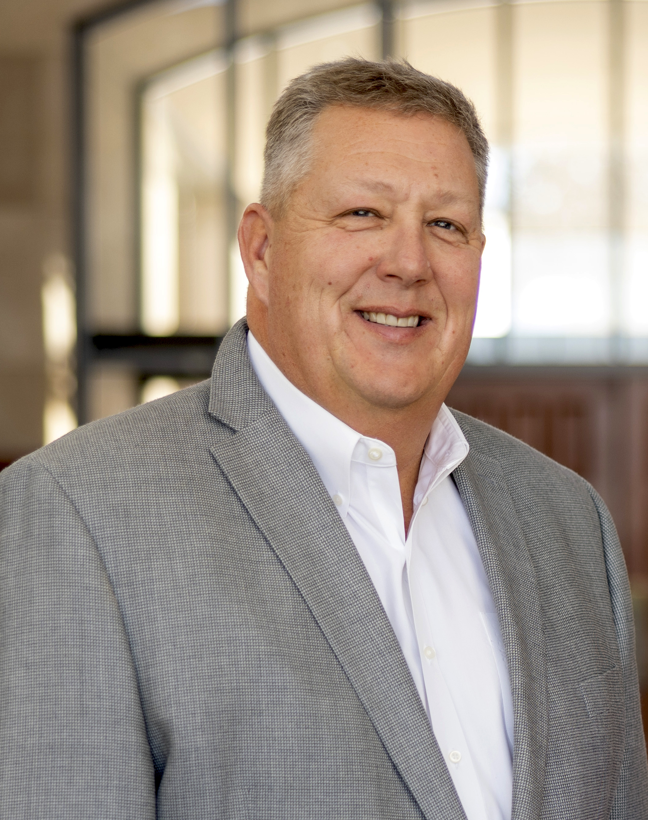 head shot of white man in gray blazer and white shirt